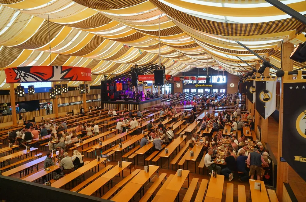 Innenansicht eines Bierzelts auf dem Cannstatter Volksfest mit langen Tischreihen