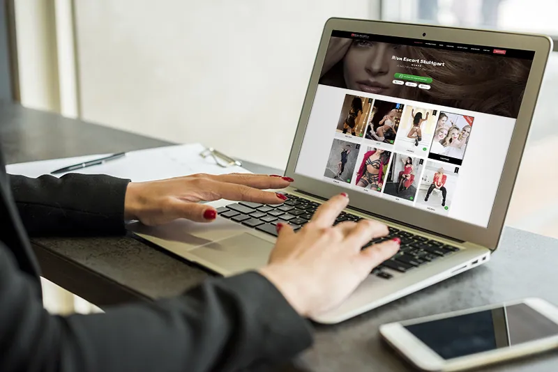 Hände einer Frau tippen auf einem Laptop, auf dem eine Agentur-Website mit Profilfotos geöffnet ist