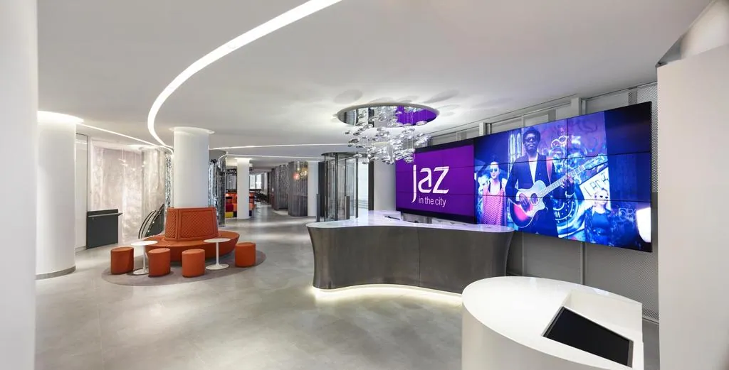 Lobby des Jaz Hotels in Stuttgart mit geschwungenem Empfangstresen und Videowand