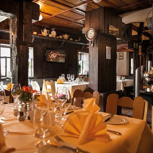 Rustikaler Speisesaal des Restaurants Ackerbürger in Stuttgart mit Holzbalken und gedeckten Tischen