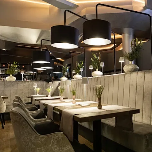 Speisesaal des Restaurants Ritzi in Stuttgart mit schwarzen Hängelampen und gepolsterten Bänken