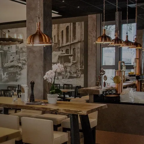 Speisesaal des Restaurants Trollinger in Stuttgart mit Holztischen und kupferfarbenen Lampen