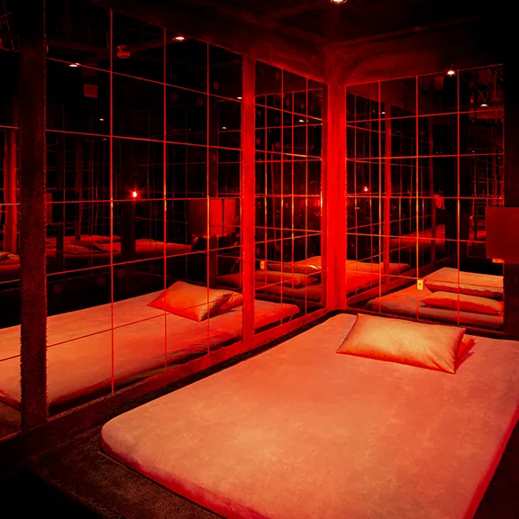 Spiegelzimmer im Sakura FKK Club in rotem Licht mit mehreren Liegeflächen