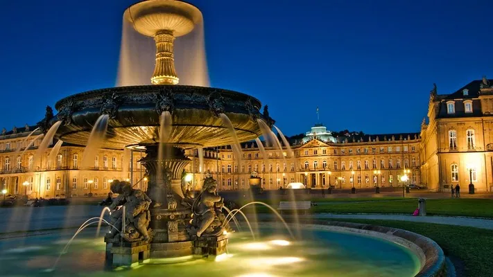 Beleuchteter Springbrunnen vor einem Barockschloss in Stuttgart bei Nacht