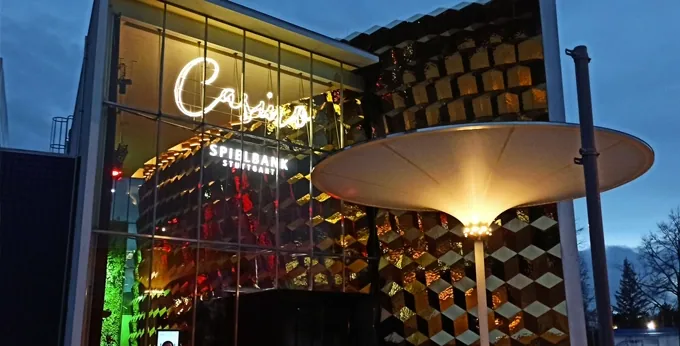 Eingang der Spielbank Stuttgart mit Casino-Schriftzug und schirmförmigem Vordach am Abend