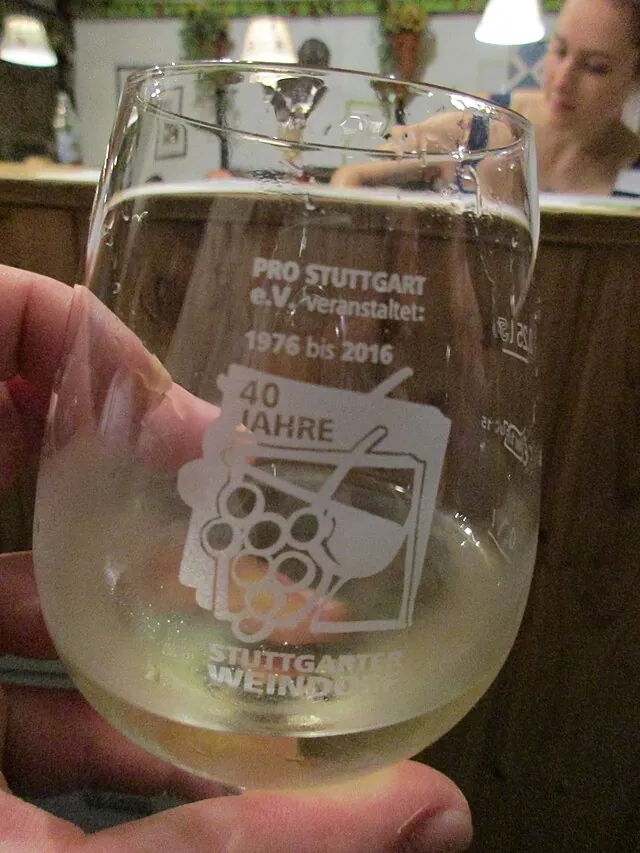 Weinglas mit dem Aufdruck „40 Jahre Stuttgarter Weindorf“ in einer Hand