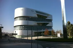 Silberne, geschwungene Fassade des Mercedes-Benz-Museums in Stuttgart vor blauem Himmel